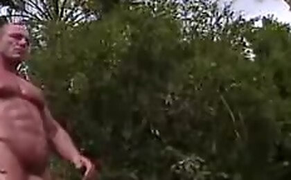 An athlete is stretching outdoors in the nude & masturbates